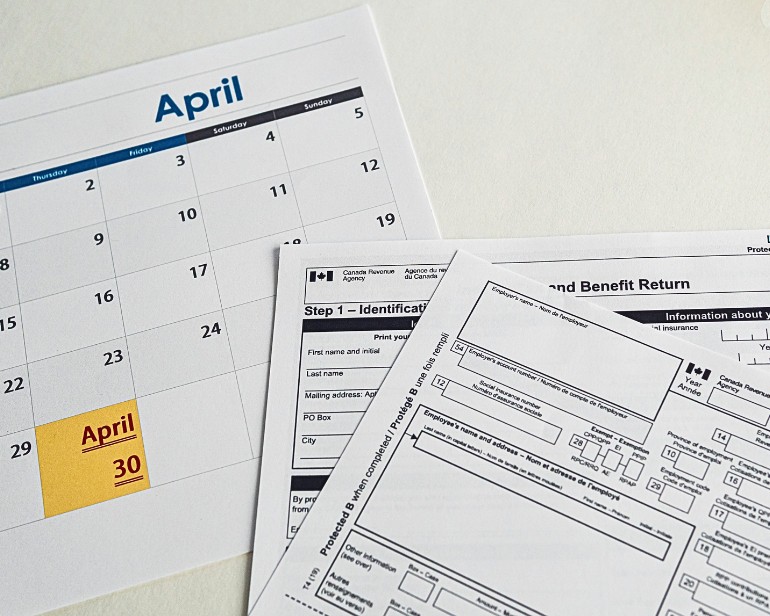 Calendar showing month of April, with 30th in yellow, under some tax forms.