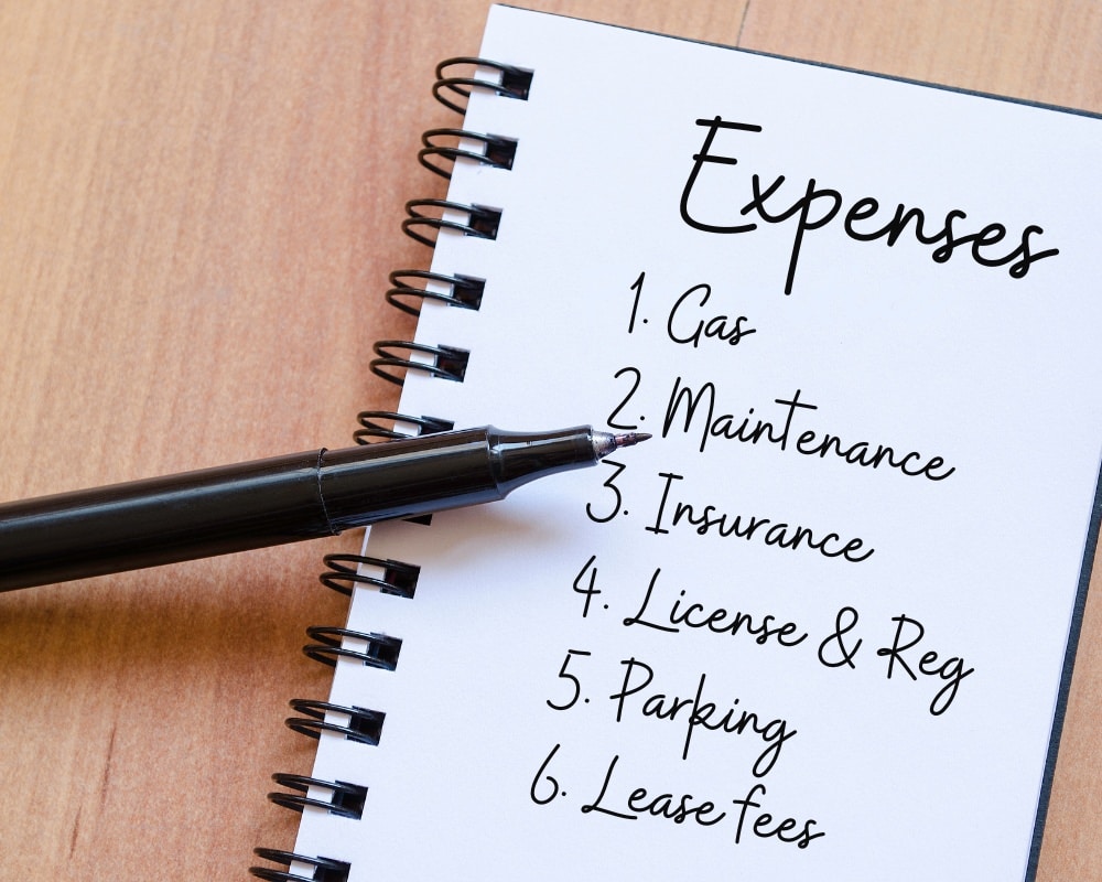 Book with list of vehicle expenses with a pen.
